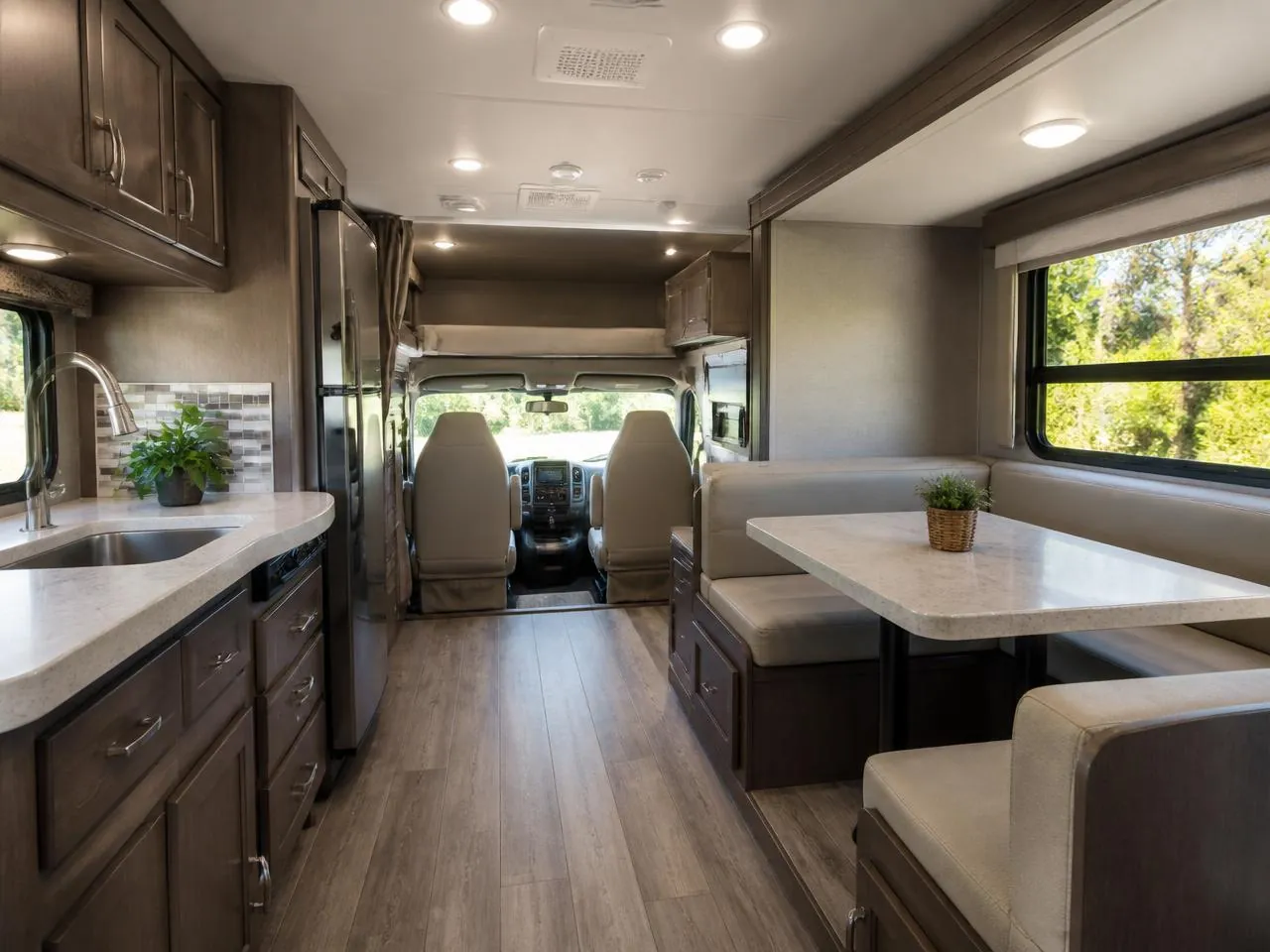 Clean RV interior with a wiped dinette table, tidy galley counter and spotless vinyl floor.